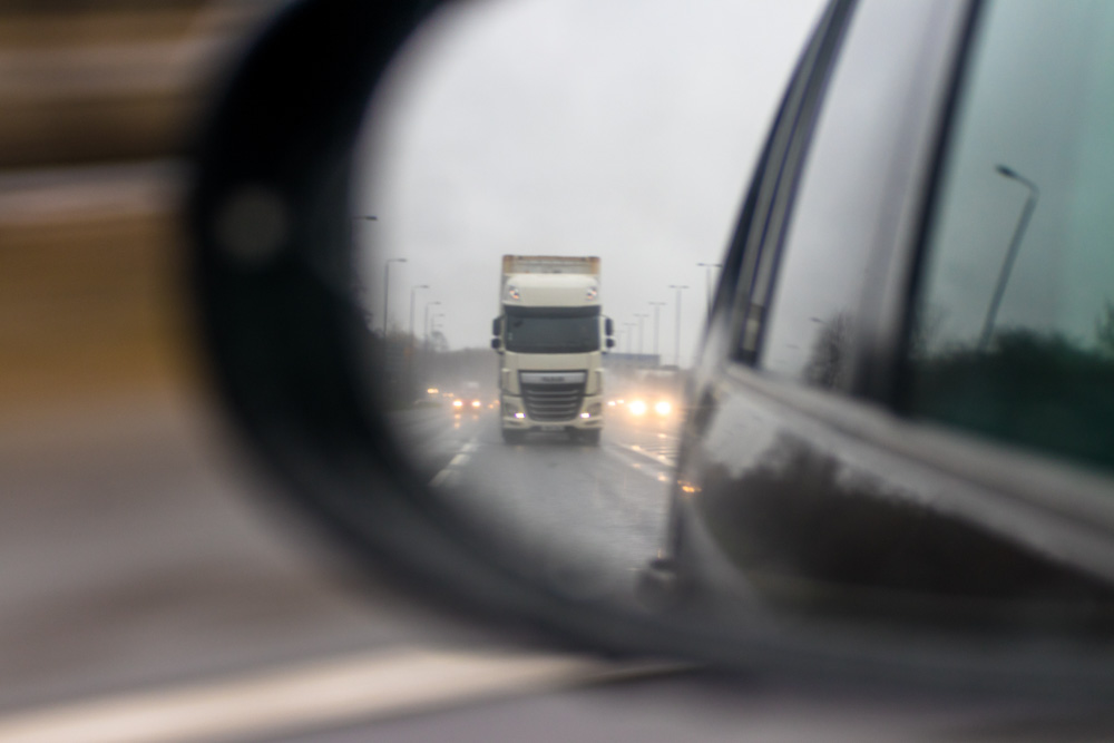 Car side or wing mirror showing large lorry